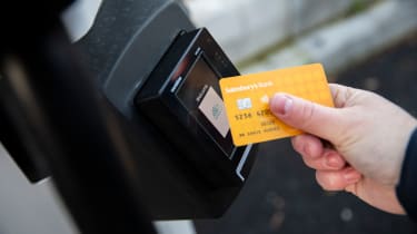 Person scanning credit card on Sainsburys EV charger contactless payment pad